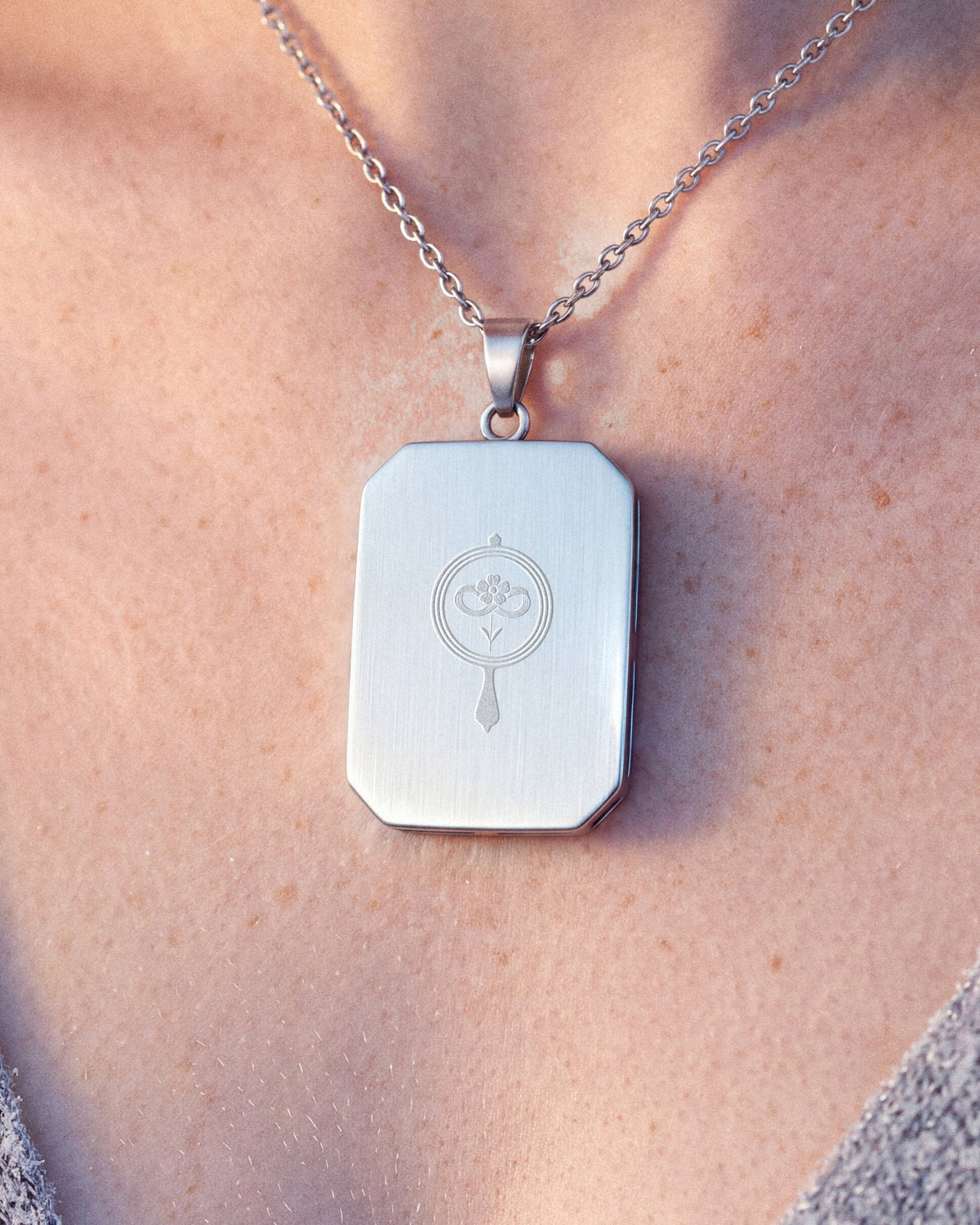 Dreamfisher, the Amulet by Mirrors by Viulet, worn, close, turned to its back, the etched symbol of the Atelier