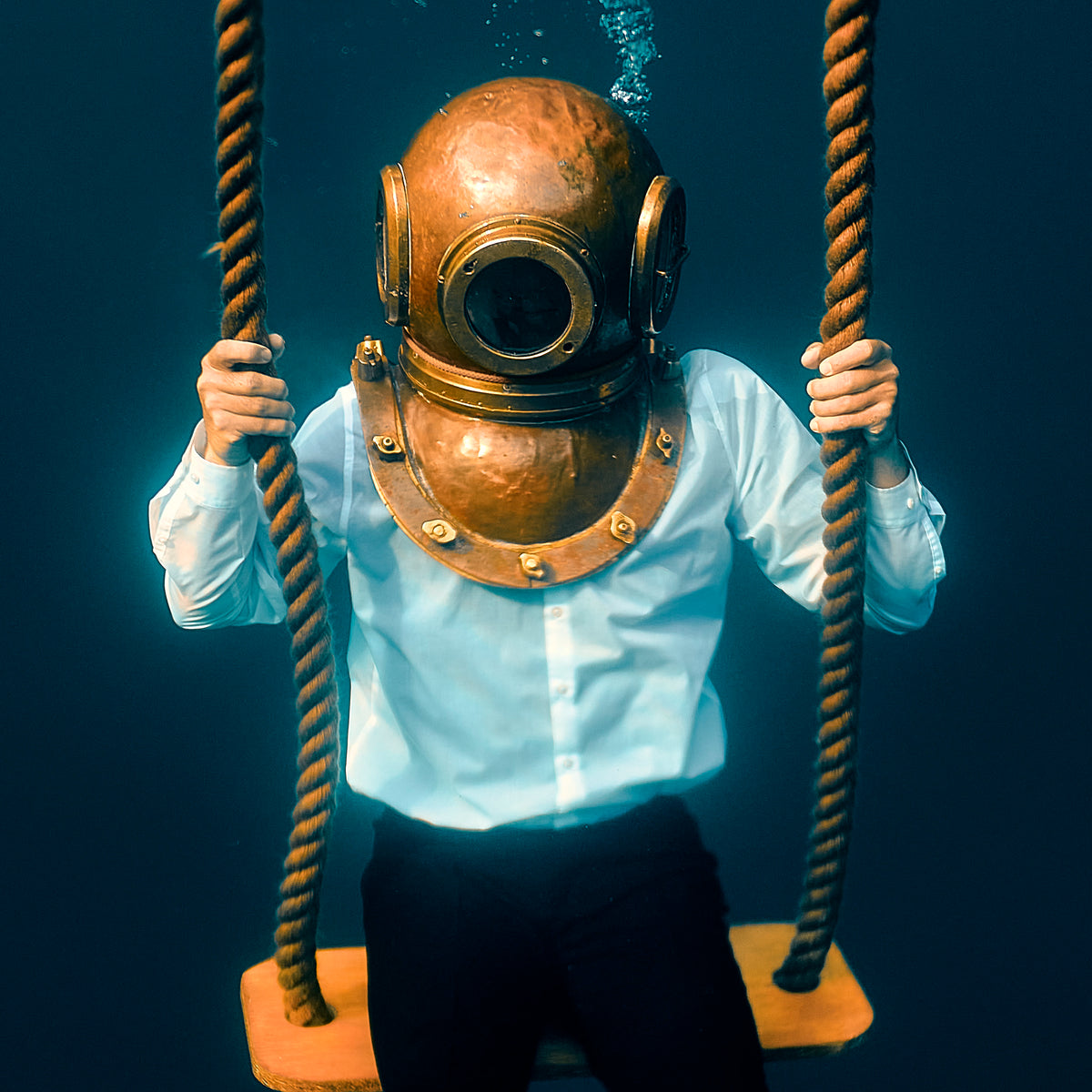 A close view of The Observer: the diving helmet, and two hands on the ropes of the swing