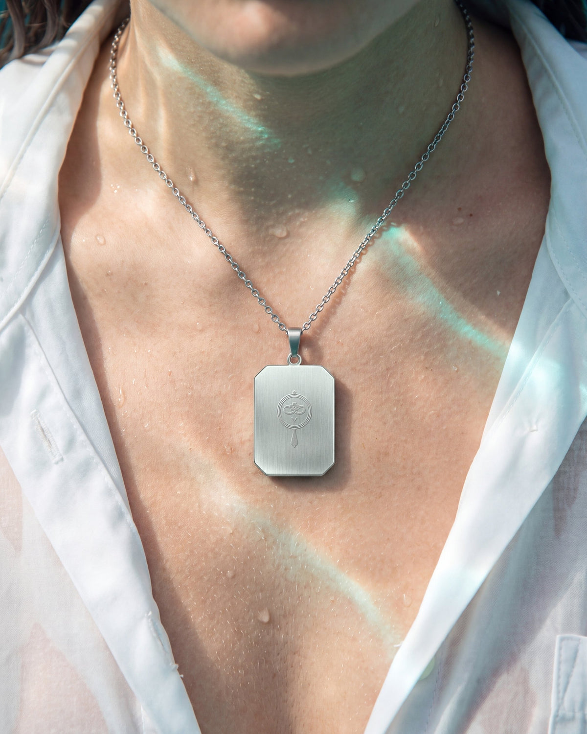 The Observer, the Amulet by Mirrors by Viulet, wet white shirt, teal light, turned to its back, the etched symbol of the Atelier