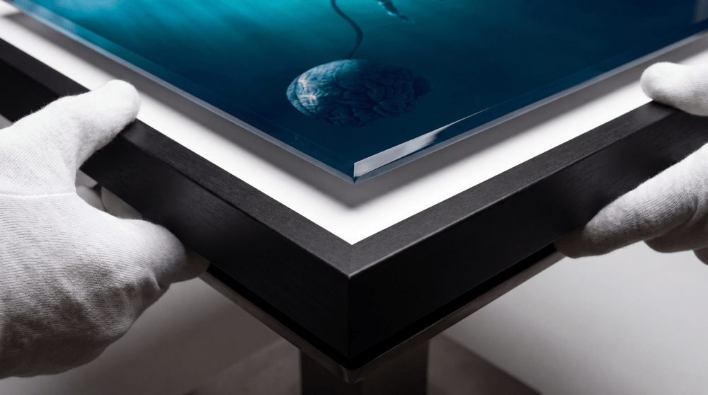 Gloved hands on the corner of The War Within: the edge of the acrylic, a white mat and a black frame