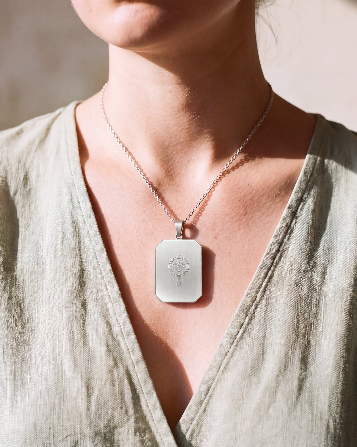 The Strawberry, the Amulet by Mirrors by Viulet, sage linen, the beam, turned to its back, the etched symbol of the Atelier