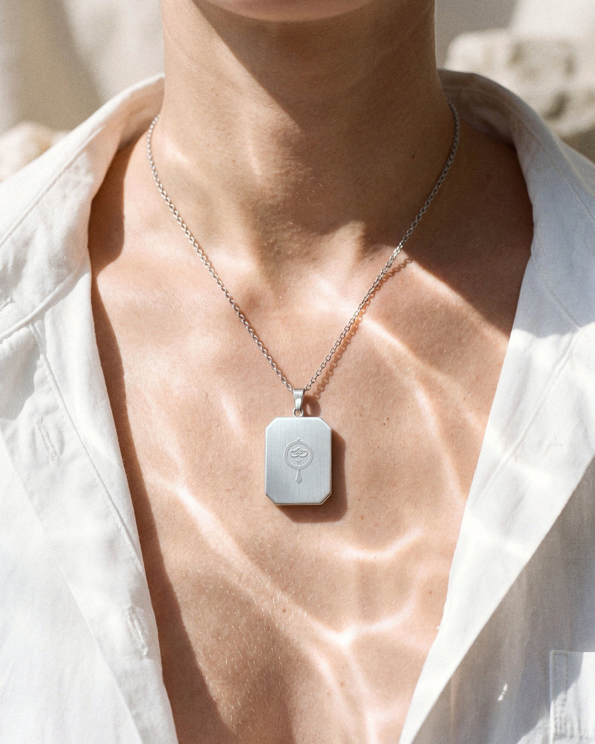 The War Within, the Amulet by Mirrors by Viulet, white cotton, turned to its back, the etched symbol of the Atelier